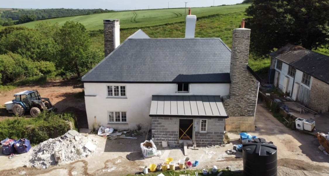 Two-storey house part-way through render and masonry work with a new zinc-effect porch roof